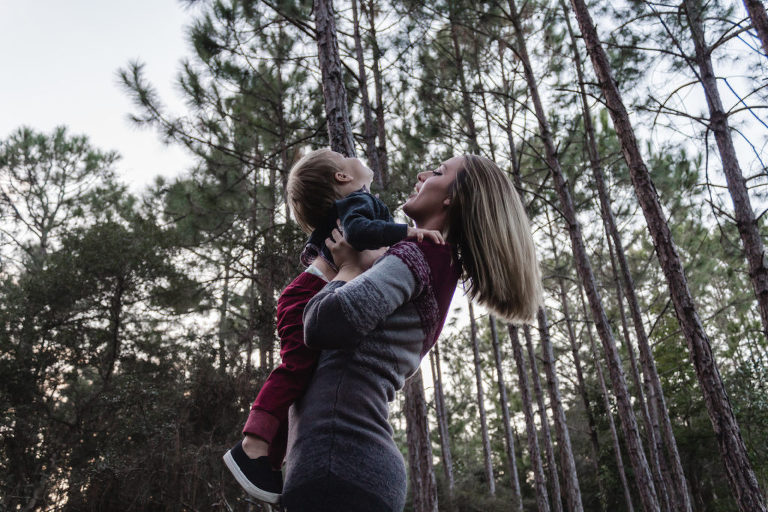 mother playing with child amongst trees