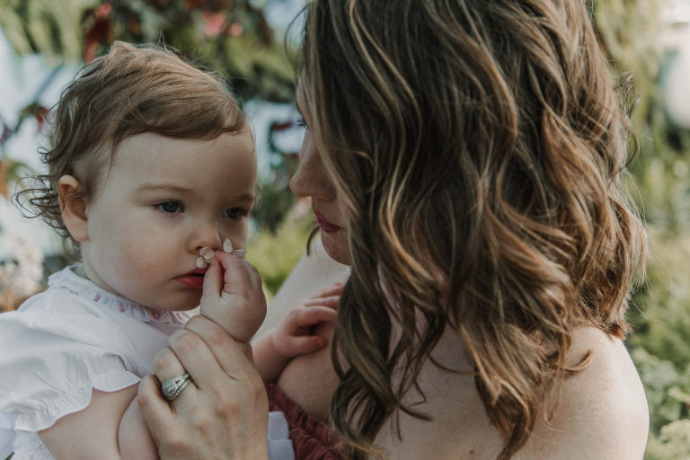 mother and daughter smelling flowers in greenhouse