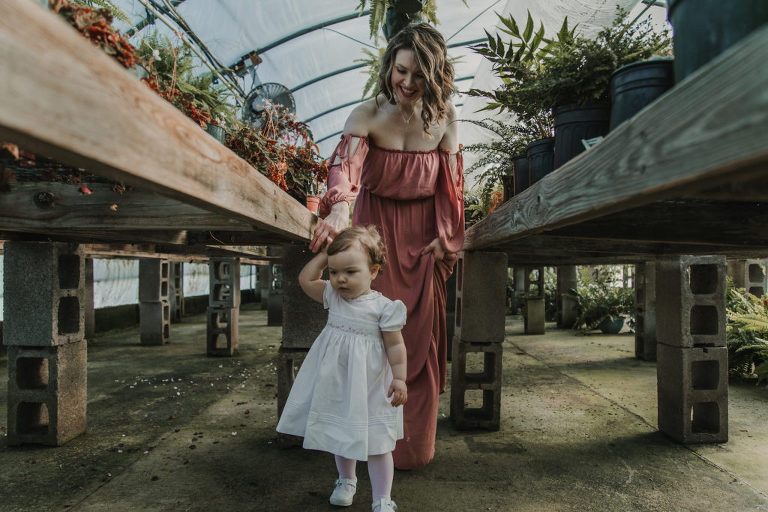 mother and daughter holding hands in greenhouse